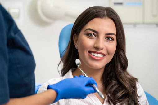 Young woman with gorgeous smile at dentist, looking at camera