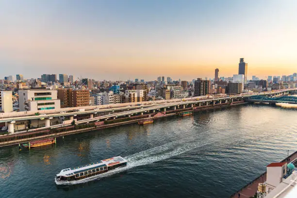Photo of Sumida river with a cruise ship at sunset in Asakusa district Tokyo city, Japan.