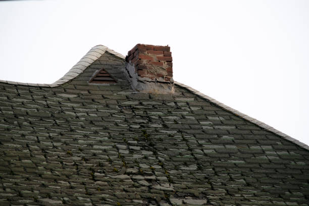 istock Damaged and old roofing shingles and chimney on a house 1162064289