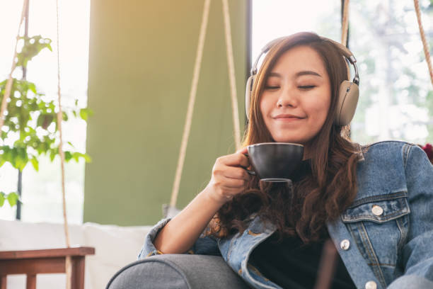 femme écoutant la musique avec le casque tout en buvant le café - fresh coffee audio photos et images de collection
