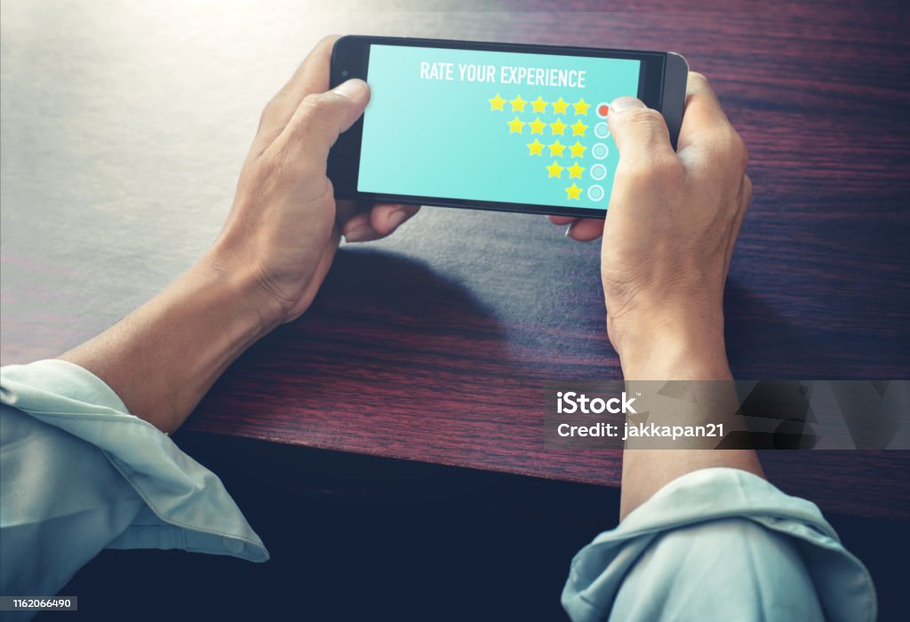 business satisfaction survey Men hand choose icon five star symbol on smart phone to increase rating of company. Customer service experience and business satisfaction survey concept. Adulation Stock Photo
