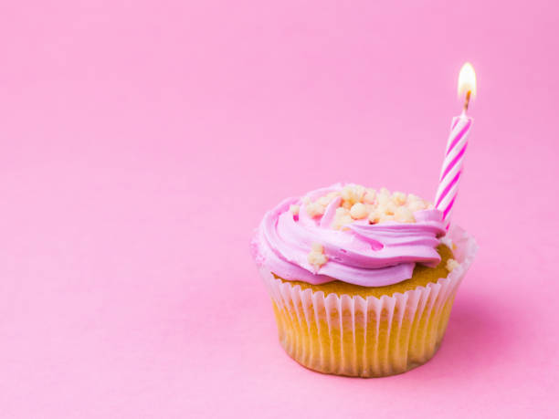 istock Pink candle in berry cupcake on pink background. 1162074893