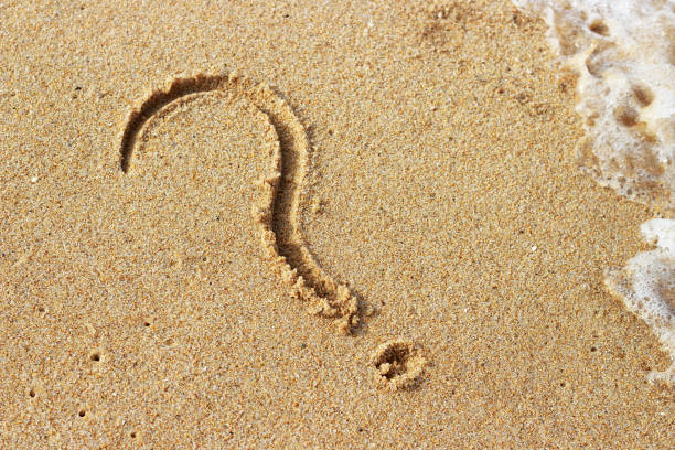 istock Question mark drawn on golden sand top view, copy space 1162078500