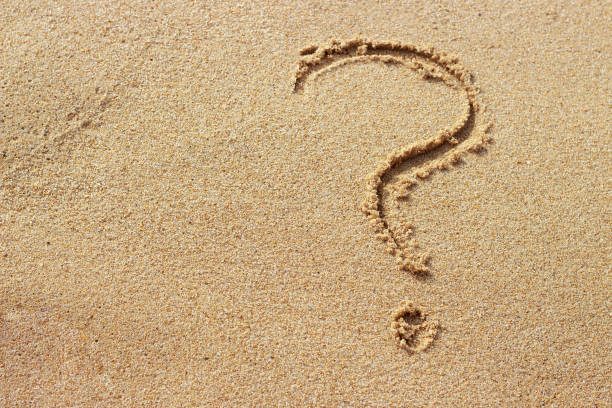istock Question mark drawn on golden sand top view, copy space 1162078501