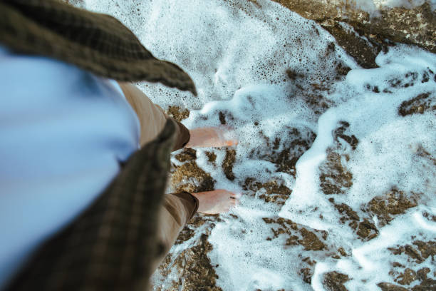 istock overhead view man barefoot walking by sea rocky beach 1162079419