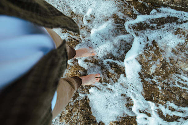istock overhead view man barefoot walking by sea rocky beach 1162079432