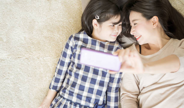 istock Mother is selfie with her little daughter using a smart phone camera while eye contact with daughter .Asian family concept 1162080083