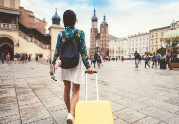 Solo traveler in Krakow Rear view of woman with suitcase and umbrella relocate to live in Krakow krakow photos stock pictures, royalty-free photos & images