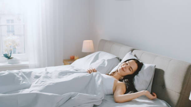 istock Attractive Brunette Cozily Sleeps in Her Bed while Early Morning Sunrays Illuminate Her. Warm, Cozy and Sweet Picture of Beauty Sleeping 1162081679