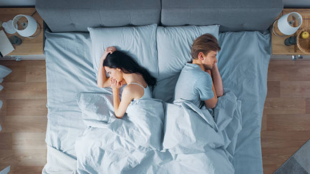 침대에서 젊은 부부 싸움, 거짓말 젊은 사람들은 서로 외면하고 원한을 들고 자신의 측면에 누워 기분을 상하게되고 - 남녀관계 문제 뉴스 사진 이미지