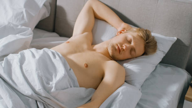 istock Handsome Fair Boy Sleeping Cozily in Bed. Young Caucasian Man Sleeping Deeply. Early Morning Sun Sines Through the Window 1162082430