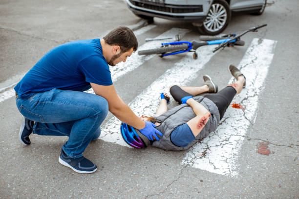 istock Road accident with injured cyclist and man providing first aid 1162083793