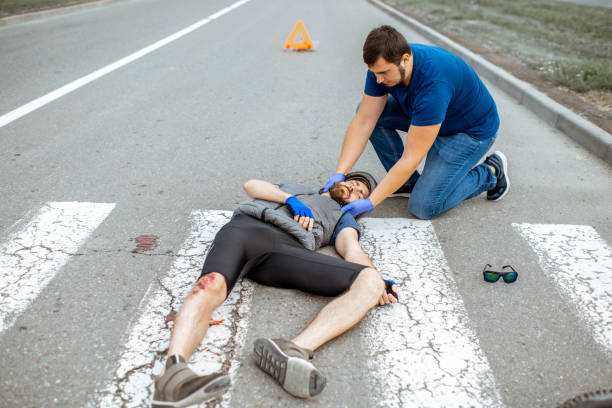 istock Road accident with injured cyclist and man providing first aid 1162083801