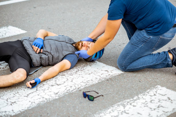 istock Road accident with injured cyclist and man providing first aid 1162083813