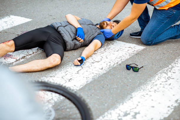 istock Road accident with injured cyclist and man providing first aid 1162083853