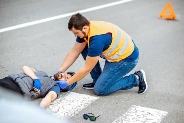 istock Road accident with injured cyclist and man providing first aid 1162083878