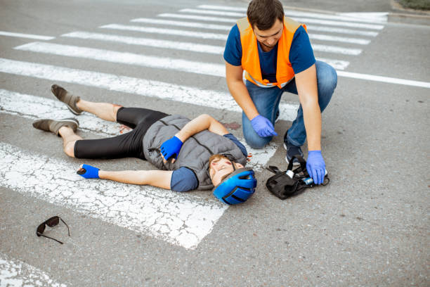 istock Road accident with injured cyclist and man providing first aid 1162083951