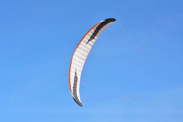 istock Big white, black and orange bow kite flying in front of clear blue sky 1162086505