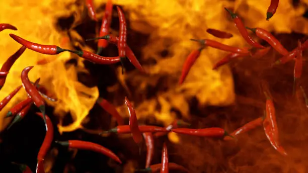Red hot chilli peppers flying in freeze motion in flames.