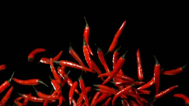 Red hot chilli peppers flying in freeze motion on black background