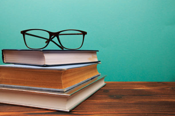 istock pile of old books with glasses panorma, good copy space  on blue background - Image 1162089577