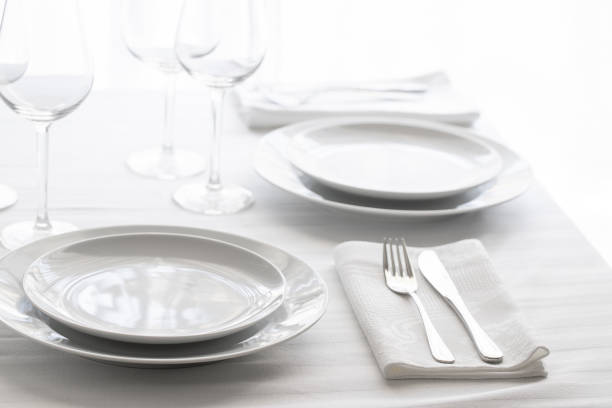istock Table setting white and grey colour. Empty glasses and plates set with napkin and cutlery. Restaurant interior background. 1162091718