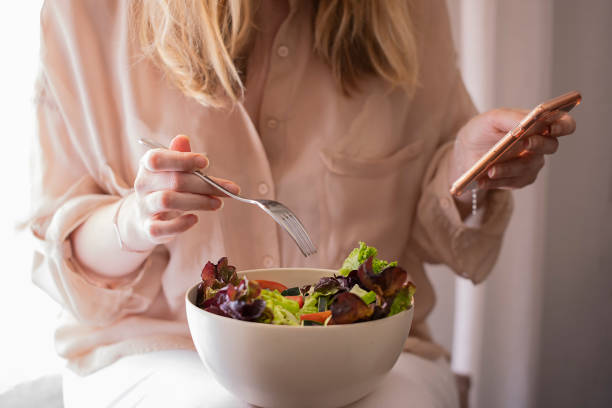 istock Woman is using an app in her smartphone device, while eating a green salad. 1162092161