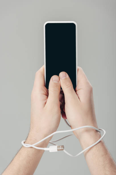 istock cropped of man with usb cable on hands holding smartphone with blank screen isolated on grey 1162101685