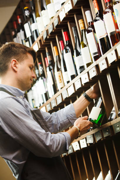 istock Thoughtful expert in winemaking on background of shelves with wine. 1162101837
