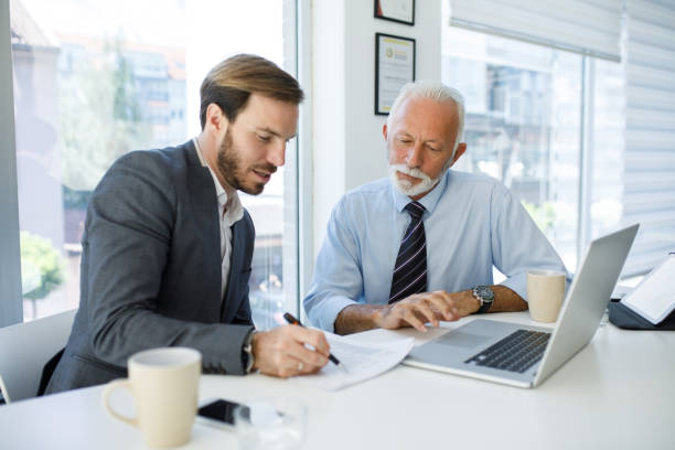 istock Young businessman cooperating with experienced colleague in the office 1162102801