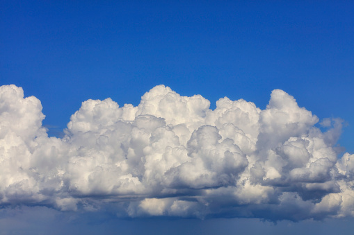 In the blue sky a white-gray fluffy cloud gradually gathering rain.