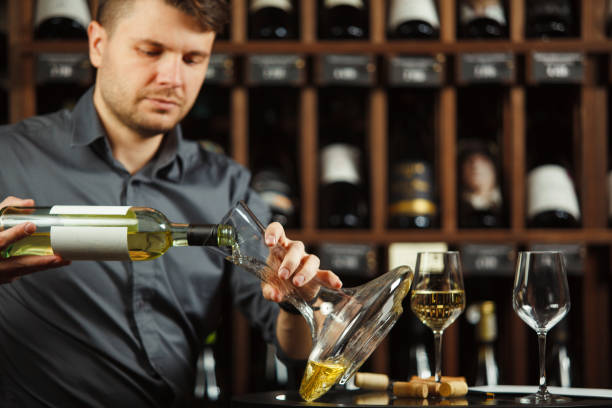 istock Male sommelier pouring white wine in decanter 1162103342