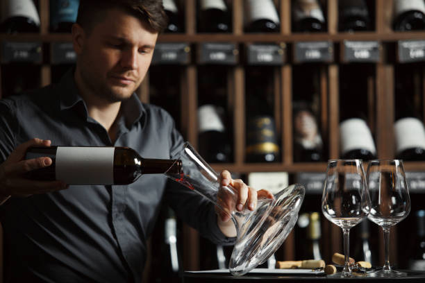 istock Serious sommelier pouring red wine in decanter 1162104029