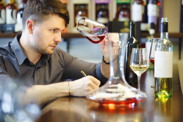istock Male sommelier tasting red and white wine, making notes at bar counter 1162104595