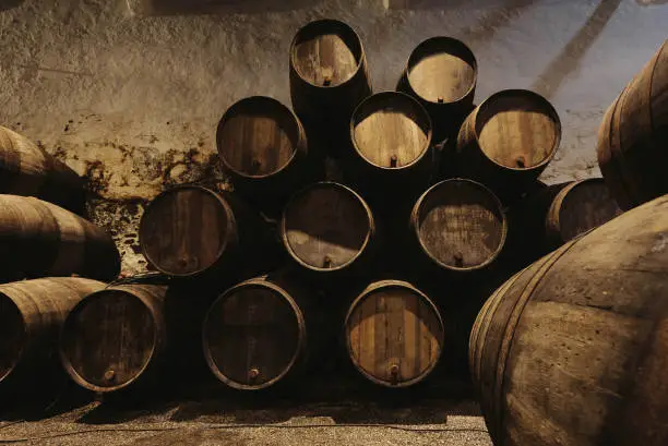 Photo of Old winery with wooden barrels full of port wine inside. Dark cellar for winemaking, Portugal