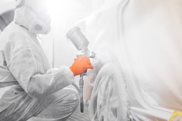 istock Male worker with mask and protective clothes painting car using spray compressor. 1162107455
