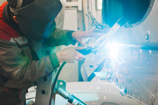 istock Welder in protective mask welds car body. 1162108361