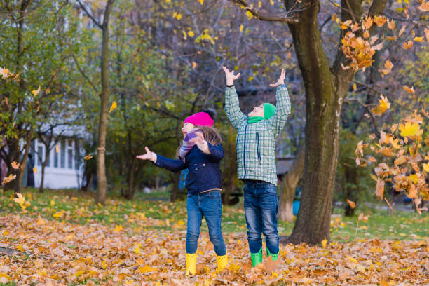 istock Two children play with maple leaves in park 1162108739