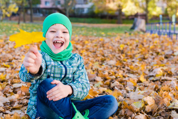 menino de sorriso feliz com folha de plátano ao ar livre - maple leaf green outdoors - fotografias e filmes do acervo