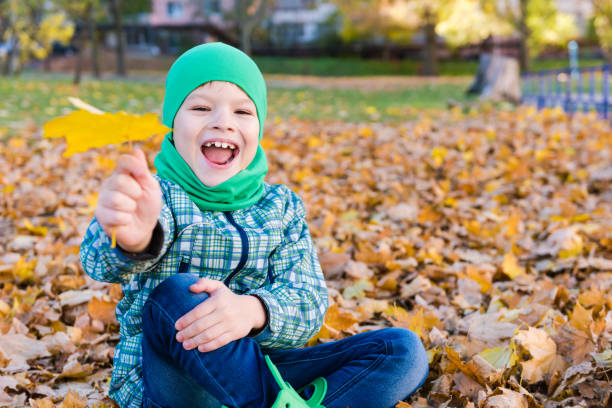 menino de sorriso feliz com folha de plátano ao ar livre - maple leaf green outdoors - fotografias e filmes do acervo