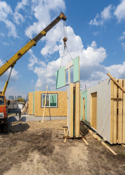 istock Process of construction new and modern modular house from composite sip panels. Vertical photo of crane with wall against blue background sky 1162108915