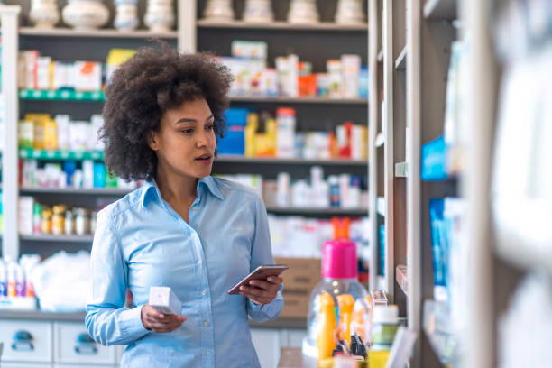 frau kaufen kosmetik in apotheke geschäft. frau nutzt smartphone in der apotheke - shelf pharmacy people indoors stock-fotos und bilder