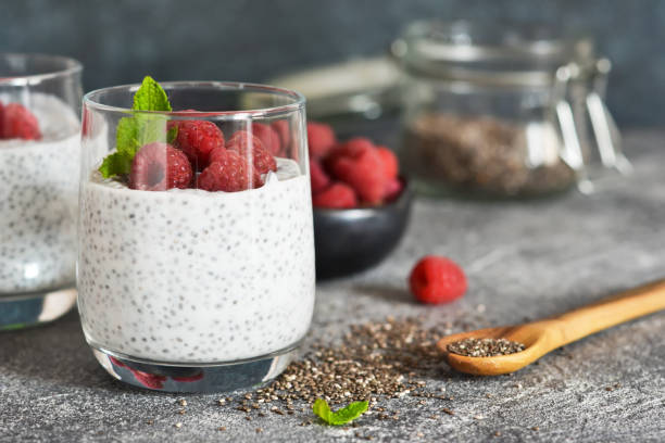 Chia pudding with yogurt and raspberries in a glass on concrete background stock photo