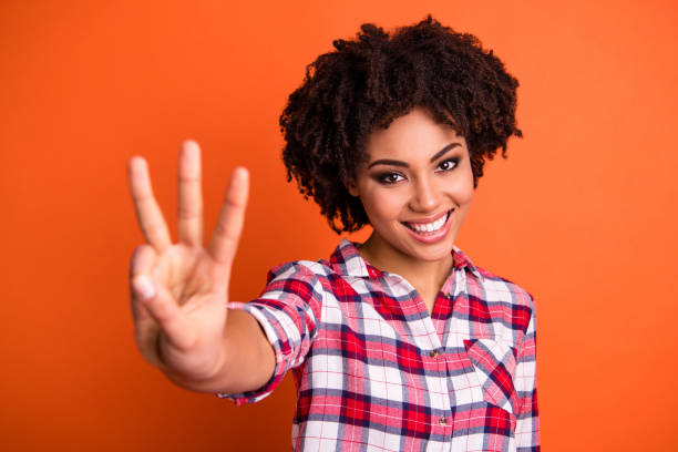 verticale de plan rapproché de son fond orange lumineux-regardant beau-regardant joli mignon gai gai gai ondulé utilisant la chemise vérifiée donnant 3 signe s'isoler au-dessus du fond orange lumineux lumineux de brillance - doigt humain photos et images de collection