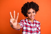 Close-up portrait of her she nice-looking attractive lovely cute cheerful cheery wavy-haired lady wearing checked shirt giving 3 sign isolated over bright vivid shine orange background