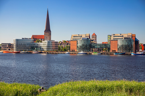 Cityscape image of Rostock riverside with St. Peter's Church during sunny summer day.