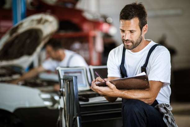 istock Young mechanic going through checklist in auto repair shop. 1162110551