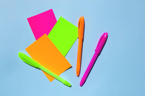 Neon colorful sticky note paper and pen on blue background.