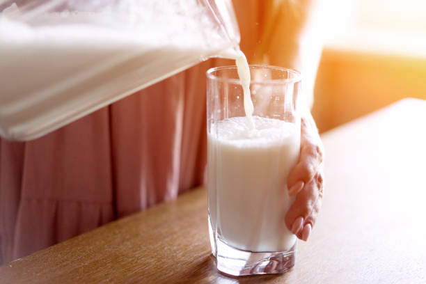 istock woman's hand pours milk into a glass from a decanter 1162111481