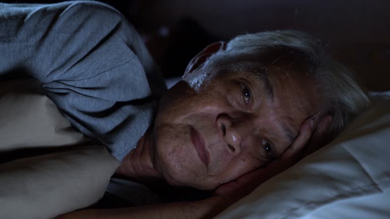 A depressed senior man lying in bed cannot sleep from insomnia